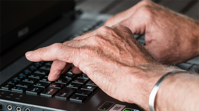 Ältere Hände an einer Notebooktastatur