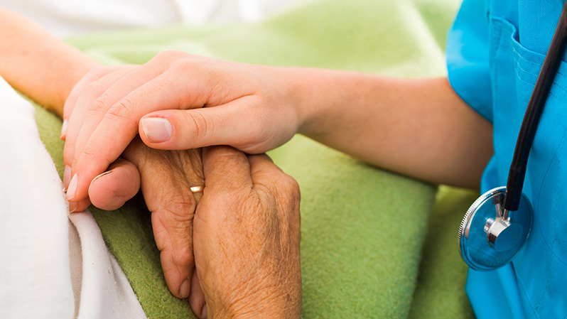Krankenschwester hält älterem Patienten die Hand