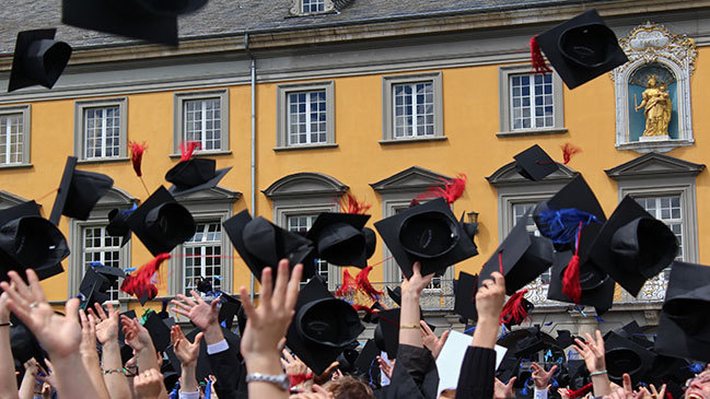 Universitätsabsolventen, Hüte fliegen in die Luft